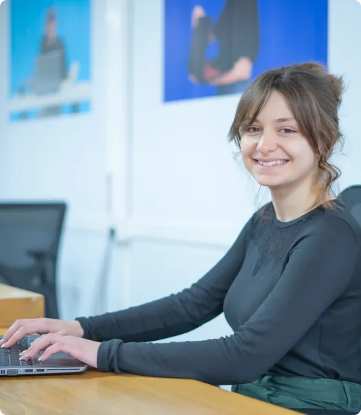 Jeune femme souriante devant un PC pour le cours sur python
