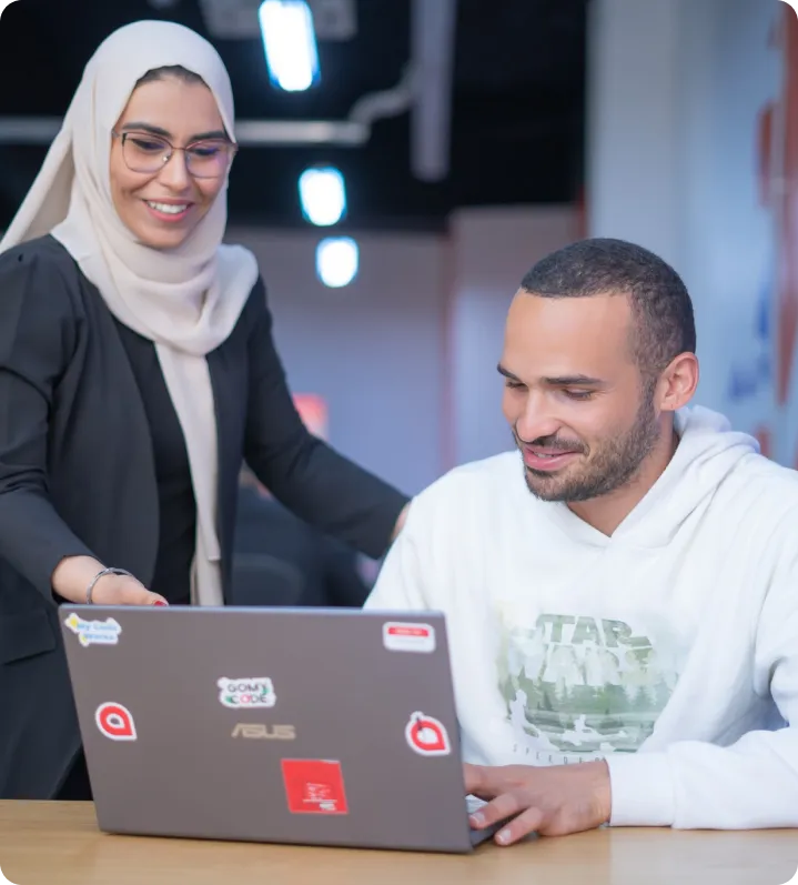 Homme assis avec une femme debout à ses côtés sur un ordinateur pour le cours de generative IA
