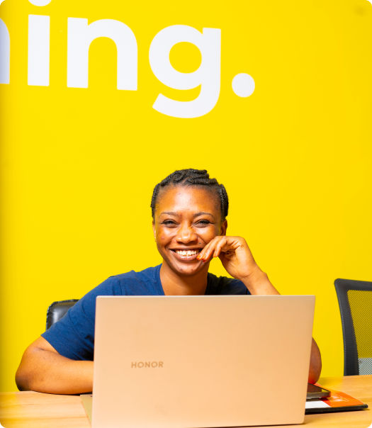 Femme noire assise sur fond jaune grand sourire qui travaille la cybersécurité.