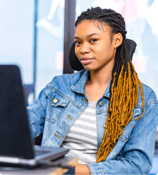 Femme noire assise devant son ordinateur pour l'introduction à l'intelligence artificielle