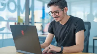Homme à lunettes assis devant son ordinateur pour l'introduction à la cybersécurité