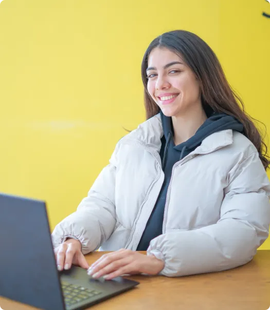 Femme souriante sur fond jaune devant son ordinateur pour une introduction au social media